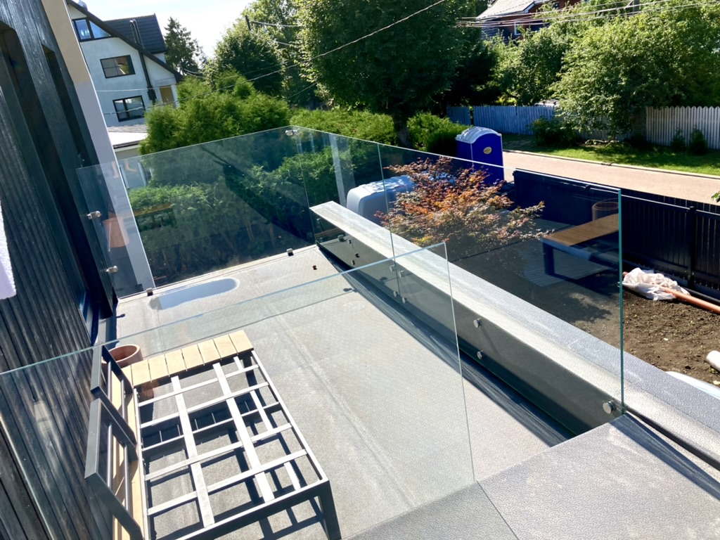 Läbipaistev klaaspiire ehitusjärgus katuseterrassil, all paistab basseiniala